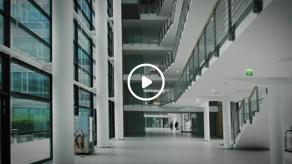 Video still: Modern interior in a spacious building with large glass windows, a curved staircase and minimalist decor.